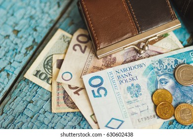 Polish zloty with little wallets on the old wooden background, soft focus background