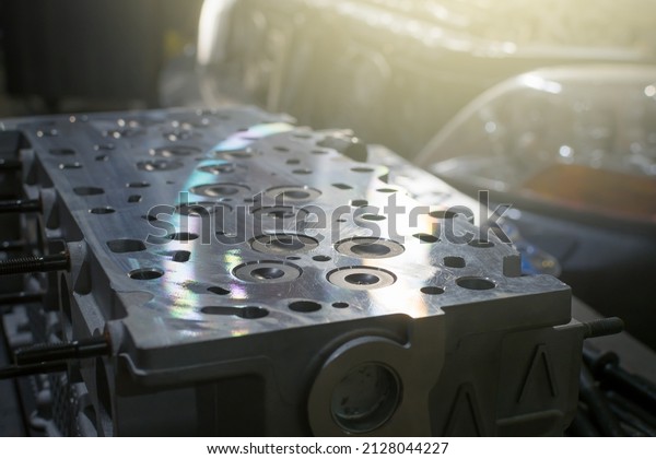 Polished cylinder head with gasket on a table in\
a car repair shop. Blur\
effect.