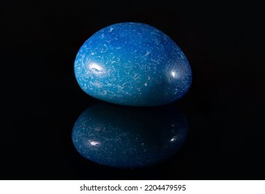 A Polished Piece Of The Blue Agate Mineral With Light Inclusions On The Surface. Isolated On Black Background.