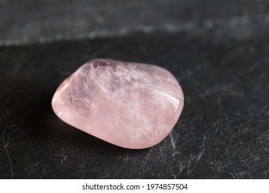 Polished, rolled, translucent  rose quartz pebble on gray slate background