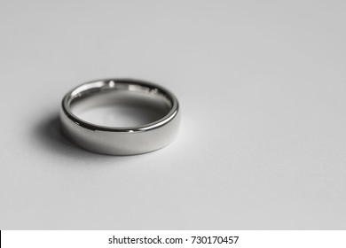 Polished Silver Coloured Wedding Band Ring Against A White Surface.