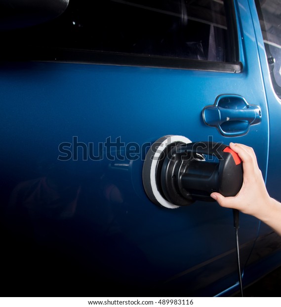 Polishing\
the blue car with polish machine in the\
garage