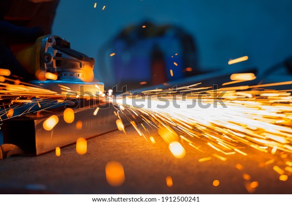polishing and\
grinding a cut metal professional pipe with sparks in the workshop\
with a shallow depth of\
field