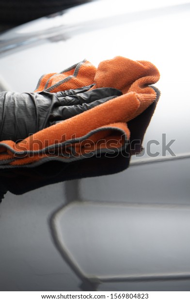 polishing the hood of a car with a orange\
cloth so you can see the reflections\
