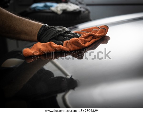 polishing the hood of a car with a orange
cloth so you can see the reflections
