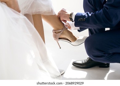 polite man helps a woman to put on her shoes. The groom takes care of his bride and on the wedding day neatly buttons up women's high-heeled shoes. Female shoes and male hands close up - Powered by Shutterstock