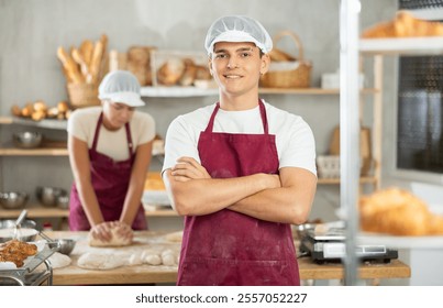 Polite young male baker welcoming clients with friendly smile in bakehouse - Powered by Shutterstock