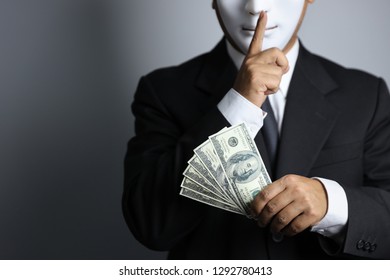 Politician Or Businessman Wearing Black Suit And White Mask Show Banknotes As A Promise Of Buying Vote Of The Upcoming Elections And Do Not Tell To Anyone