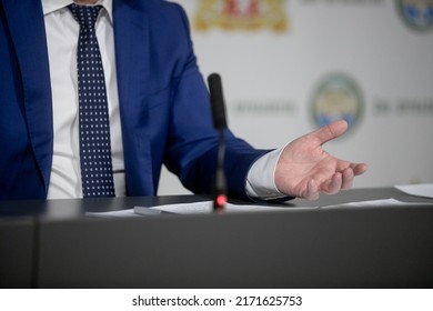 Politician With Clasped Hands Sitting Behind Desk.