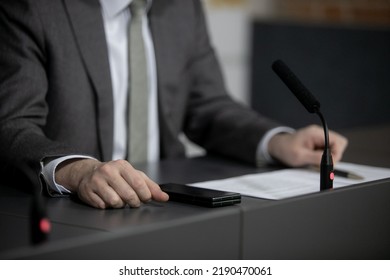 Politician With Clasped Hands Sitting Behind Desk.