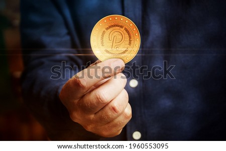 Polkadot cryptocurrency symbol golden coin in hand abstract concept.