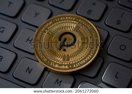 Polkadot DOT Cryptocurrency Physical Coin placed on computer keyboard and lit with light.