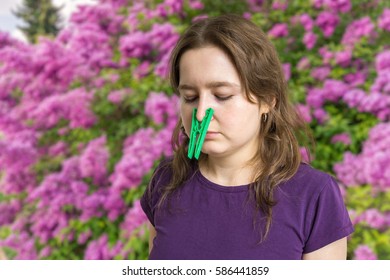 Pollen Allergy Concept. Young Woman Cant Breathe And Wearing Peg On Her Nose. Flowers In Background.