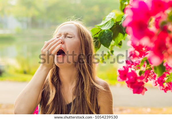 花粉アレルギーのコンセプト 若い女はくしゃみをする 背景に花の木 の写真素材 今すぐ編集