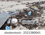 A polluted beach on Ko Samui, Thailand, littered with plastic bottles, food containers, and various types of debris. This image highlights the environmental issue of plastic waste and marine pollution