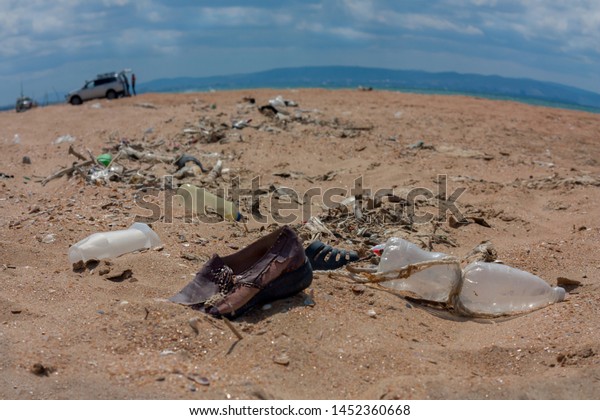 Polluted planet full\
of plastic bottles and other garbage left by people, a car and a\
few persons on the background. Planet pollution, environmental\
problem, contamination
