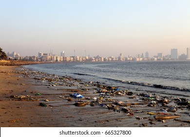 Polluted Sea Front Beach in Mumbai with rubbish and plastic bags and trash along the coastline with skyline in the background - Shutterstock ID 665327800