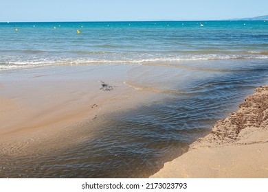 Pollution Of Beach By Dirty Water Flowing On Sand In Sea .