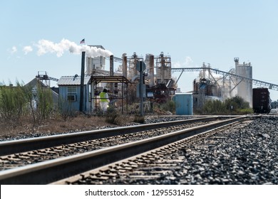 Pollution And Climate Change. Factory In Texas Producing Fossil Fuel Smoke Stack And Train Tracks Leading To Industrial Revolution Style Like In Austin Texas