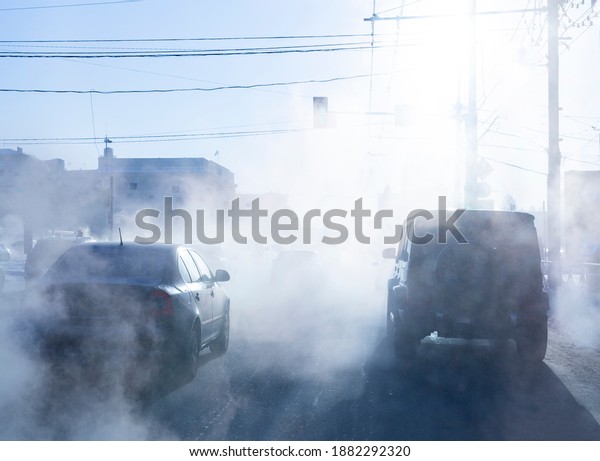 pollution from the exhaust of cars\
in the city in the winter. Smoke from cars on a cold winter\
day