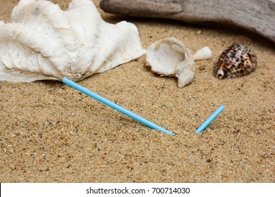 Pollution of plastic straws and fork left on beach background with beautiful seashells and drift wood.  Plastic pollution is harmful to  marine lives. Environmental concept.  Ban single use plastic.