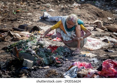 Pollution And Poverty. Indian Old Female Warming Up Herself Near Fire In Urban Industrial Garbage On 13 Feb, 2012. Kanpur, India