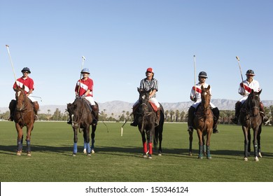 Polo players and umpire mounted on horses on field
