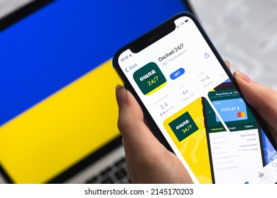 Poltava, Ukraine - April 8, 2022: Oschad bank in Ukraine. Mobile banking app for Ukraine users. Flag background, mobile phone with icon close-up view phot