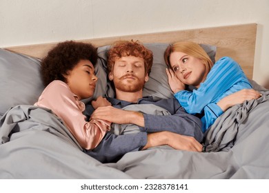 polyamorous relationship, polygamy, understanding, three adults sleeping together, redhead man and multicultural women in pajamas, bedroom, cultural diversity, acceptance, bisexual