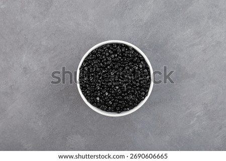 Polyethene or poly(methylene) granules, top view. Other names: Polyethylene, Polythene. Black masterbatch, PE pellets. Granulated plastic compound. Virgin polymer.