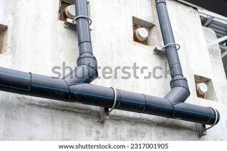 Polyethylene pipes drain water from sky train tracks. HDPE pipeline drainage. Black PE tube was installed on a building wall. Polyethylene pipe network. Pipe construction. Water drainage HDPE pipe.