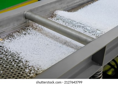 Polyethylene or propylene pellets - recycled plastic granules on conveyor belt, shale shaker of waste plastic recycling machine. Environmental protection, separation, automated technology concept