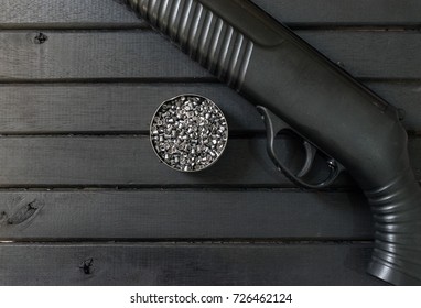 Polymer Air Rifle Gun, On A Black Wooden Background, Closeup, Showing Gun Body And Lead Pellets Inside A Tin Can, Trigger Closeup, And Textured Grip