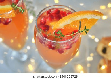 Pomegranate Mimosas for a festive brunch - a glass containing a mimosa garnished with pomegranate seeds, an orange slice and thyme - Powered by Shutterstock