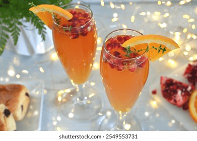 Pomegranate Mimosas for a festive brunch - a glass containing a mimosa garnished with pomegranate seeds, an orange slice and thyme - Powered by Shutterstock