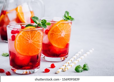 Pomegranate Orange Holiday Punch With Ice And Mint In Glass On Gray Concrete Stone Background