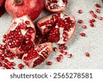 Pomegranate Seeds and Pomegranates on a Stone Gray Background Close-up.