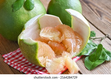 pomelo fruit on wooden background, fresh green pomelo peeled on pomelo skin and leaf frome pomelo tree , pummelo , grapefruit in summer tropical fruit  in thailand 