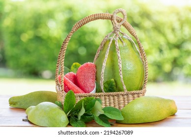 Pomelo fruit in wooden basket on blur garden background, Red Pomelo fruit with slice in wooden basket.