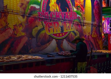 Pomona, California USA - September 23rd, 2018. A Man Is Grilling Chicken For Food Street Restaurant In LA Country Fair. Food Is Prepared For Dinner At Night Time.