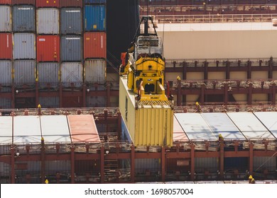 Gdańsk, Pomorskie / Poland: 10.06.2019: Drone photo of terminal crane STS loading container on one of the largest container ships in the world. Stacked Maersk containers in the backgroud.
