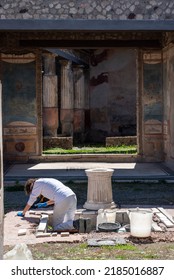 POMPEII, ITALY - MAY 03, 2022 - An Archaeologist Working On An Atrium Of A Pompeian Villa, Southern Italy