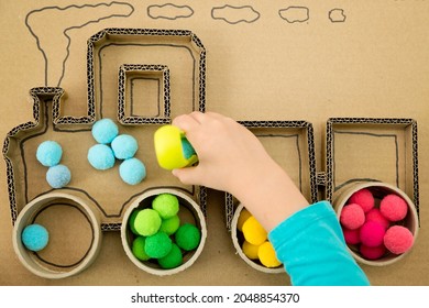 Pompom train. 3D train board for active brain exercise game made from paper core tubes and cardboard. Montessori methodology task to sort different colors.
