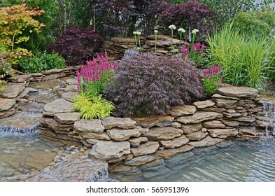 The Pond Area In An Aquatic Garden With Planted Rockery And Waterfalls