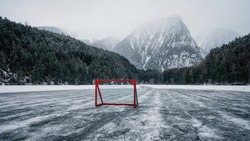 Pond Hockey On Frozen Lake.  Ice Hockey Goal On An Empty Open Air Ice-ground. Inthe Background Big Mountains 