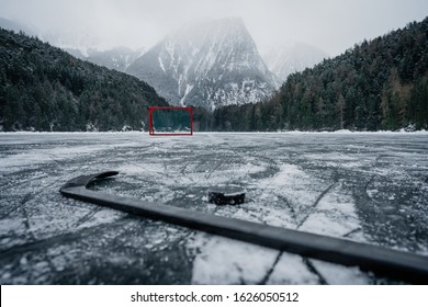 Pond hockey on frozen Lake.  Ice hockey goal on an empty open air ice-ground. Inthe background big mountains 