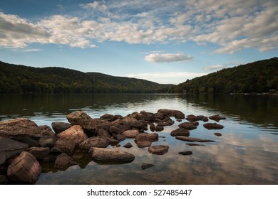 pond with rocks and cloud reflection and forest in New England