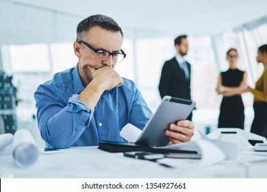 Pondering 50 Years Old Male Entrepreneur In Trendy Eyewear Reading Received Email With Bad News About Finance Problems Feeling Puzzled On Solving, Concept Of Technology And Communication