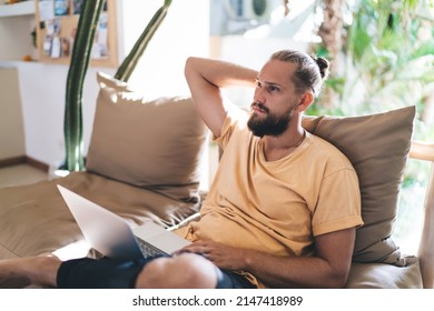 Pondering male IT software developer thoughtful looking away during remote working on laptop technology, skilled blogger with modern netbook thinking about content planning and graphic design - Powered by Shutterstock