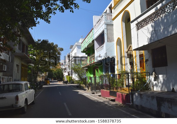 Pondicherry quiet life. Street with green trees and\
colorful facade of indian houses and villas, vintage car and\
rickshaw, sunny\
day.